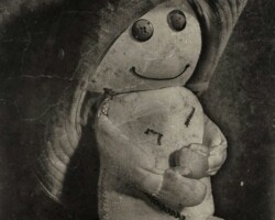 .: Hutwesen :. Artwork im Stil einer alten, teilweise zerkratzten und vergilbten monochromen Photography. Das Profil des sitzenden und lächelnden Wesens. Es trägt einen viel zu großen Westernhut auf dem Kopf.