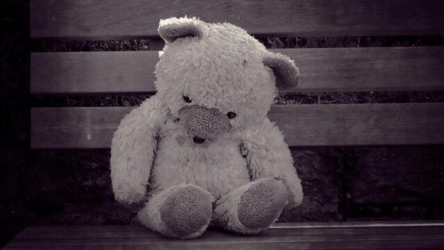 Trauriger Bär ist traurig Ein Teddybär sitz traurig geknickt, zusammngekrümmt auf einer Holzbank